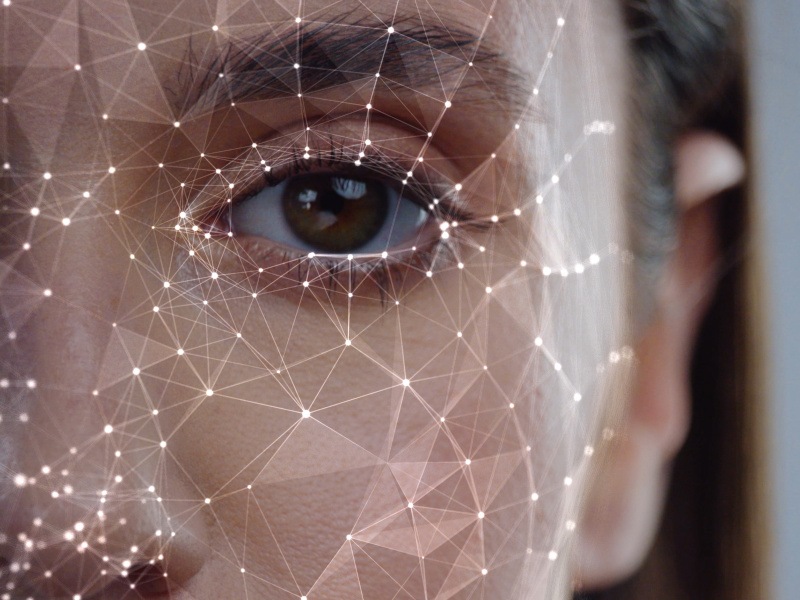 A close-up image of a woman's face with white lines around her face as if it is being scanned. Used for the concept of the AI Act and biometric systems.