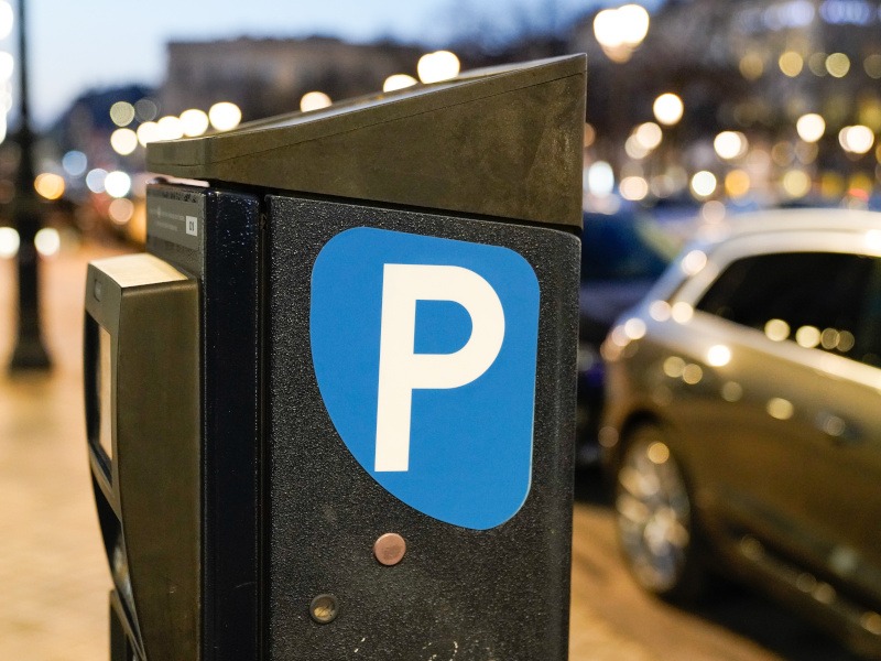 A parking metre next to cars on a road. Used for the concept of QR code phishing scams or quishing.