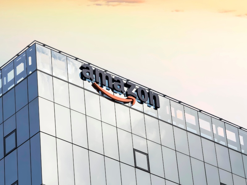 A tall building with the Amazon logo on the side and an orange sky above it.