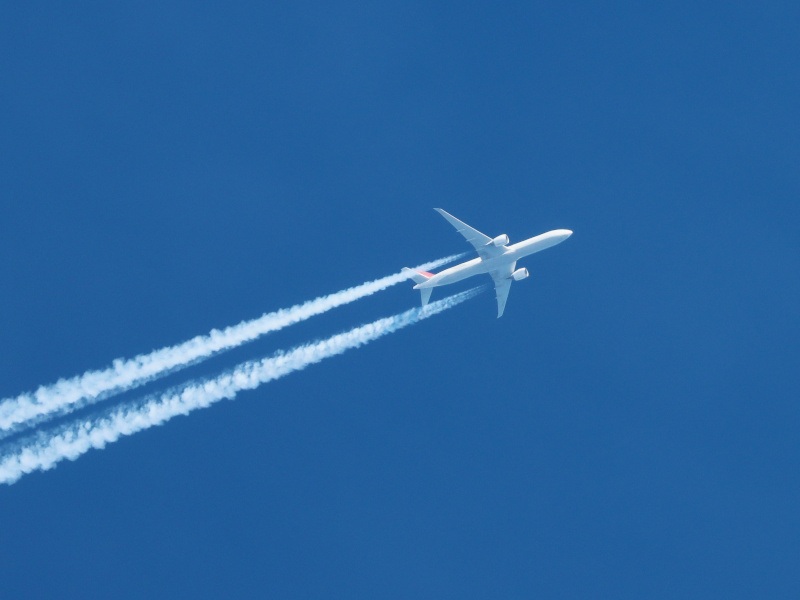 A plane flying in the sky with condensation trials behind it. Used for the context of the FlightAware breach.