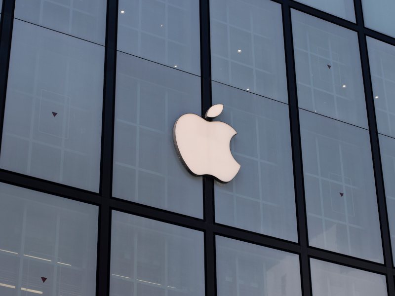 The Apple company logo on a window on the side of a building.