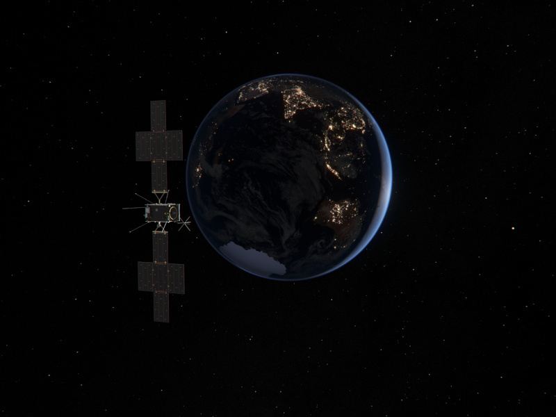 A dark photo of Earth with the JUICE spacecraft on the left in space.