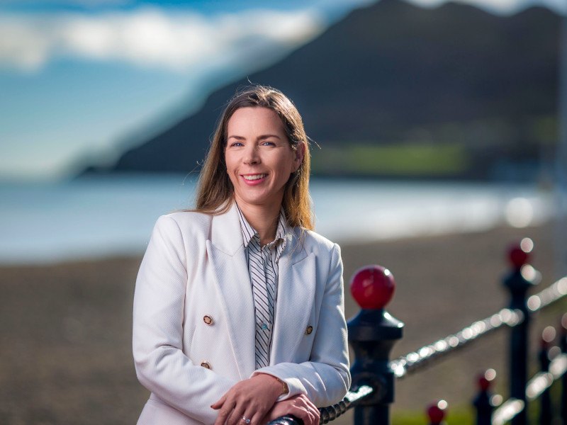 A woman leaning on a railing with a beach in the background. She is part of SD Worx Ireland.