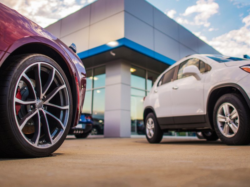 Two cars parked in front of an automotive dealership.