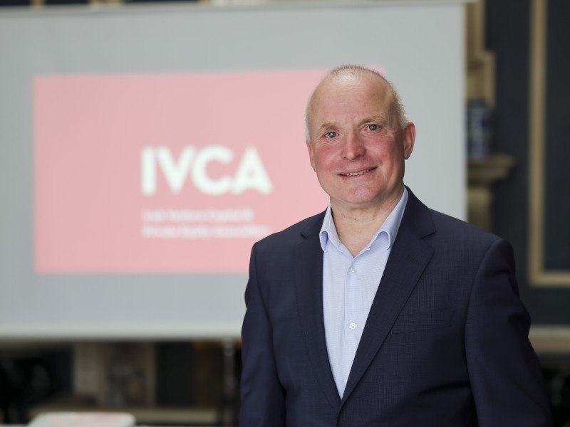 Headshot of Gerry Maguire, the new IVCA chair, with a screen in the background showing the IVCA logo.