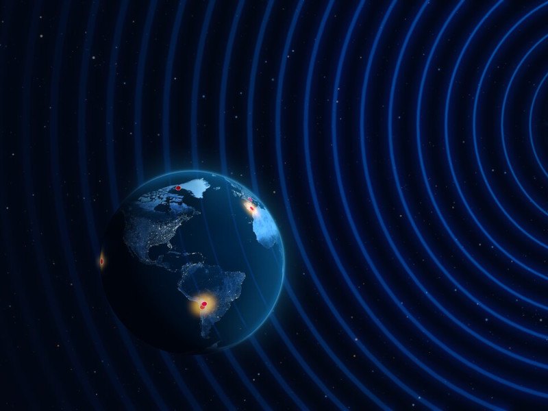 An illustration of the Earth with red dots on it and waves of light coming toward it.