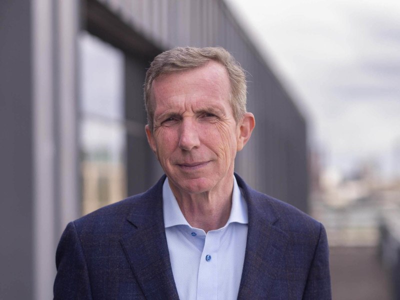 An image of Storm Technology CEO Karl Flannery, wearing a suit and standing in front of a pathway and a building.