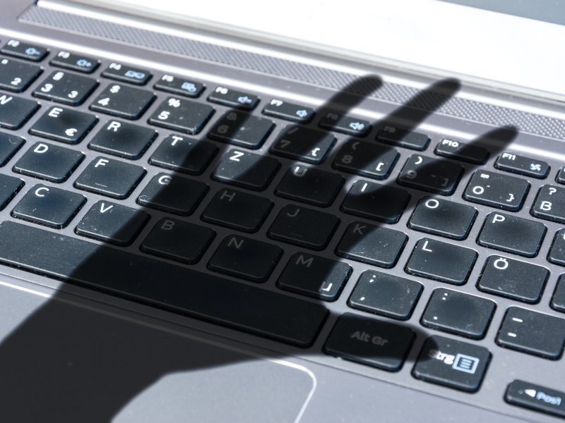 The shadow of a person's hand over a keyboard. Used for the concept of shadow IT.