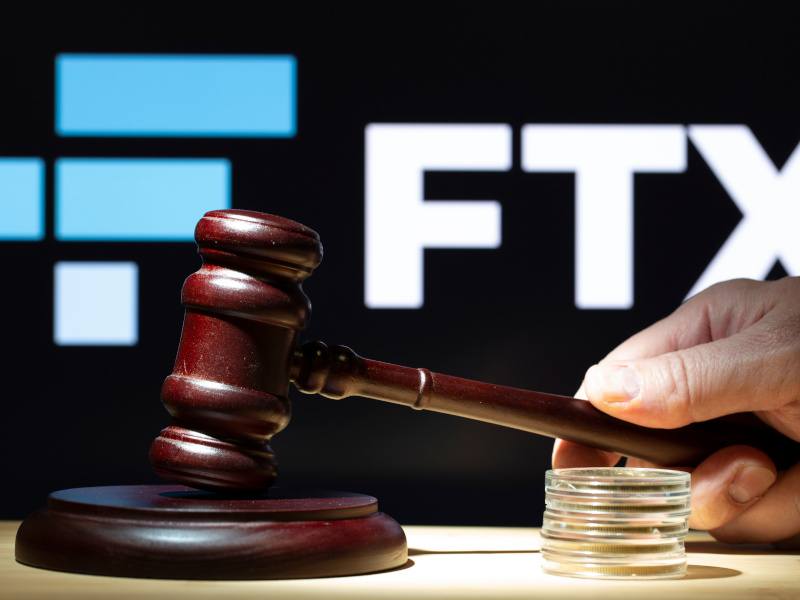 A gavel on a table with the FTX logo in the background