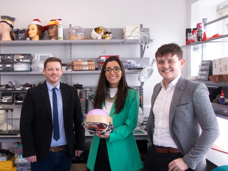 Two men and a woman standing in a small room holding a medical device. They are the founders of Luminate Medical.