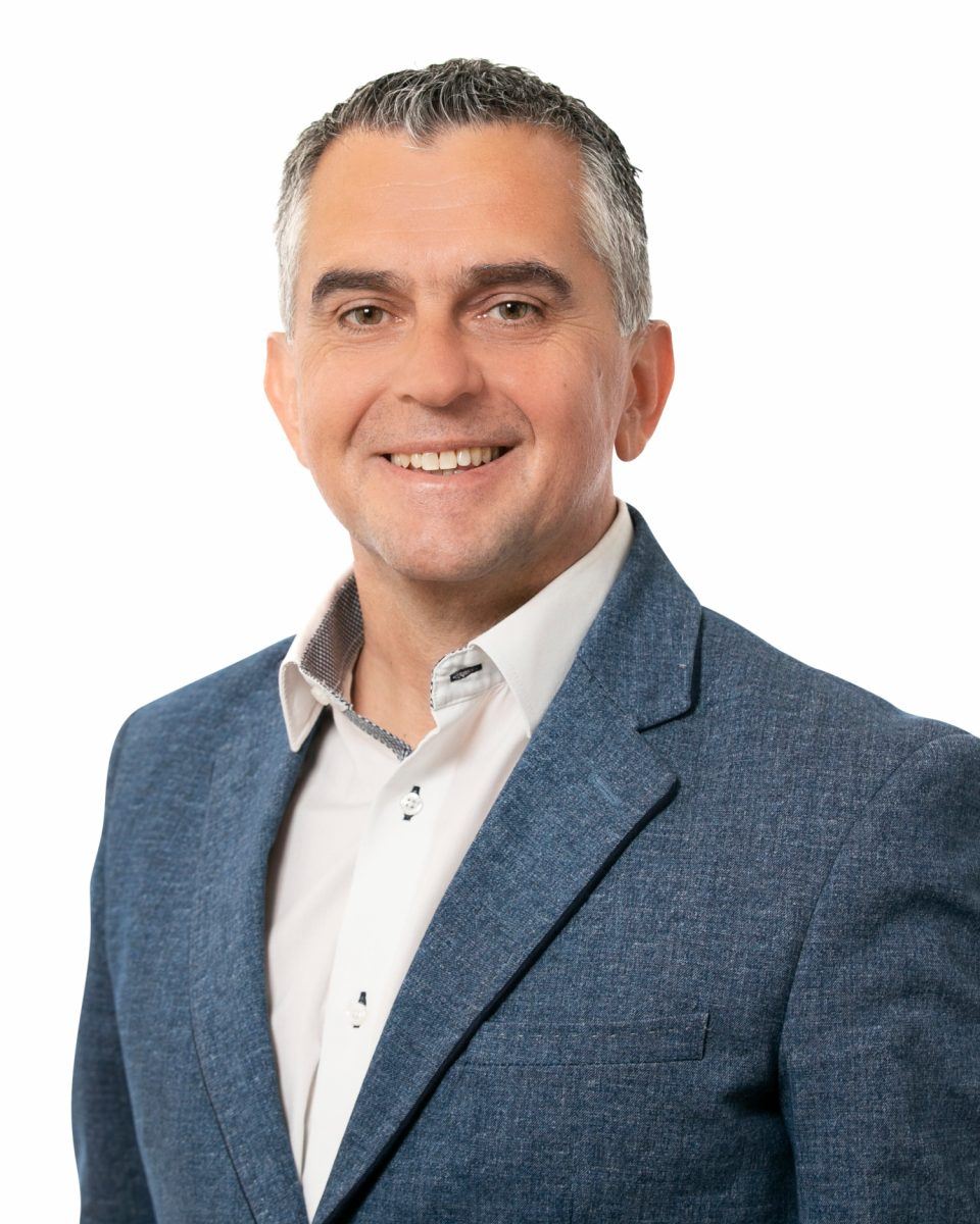 An image of Paul Swift wearing a suit and standing in a white background.