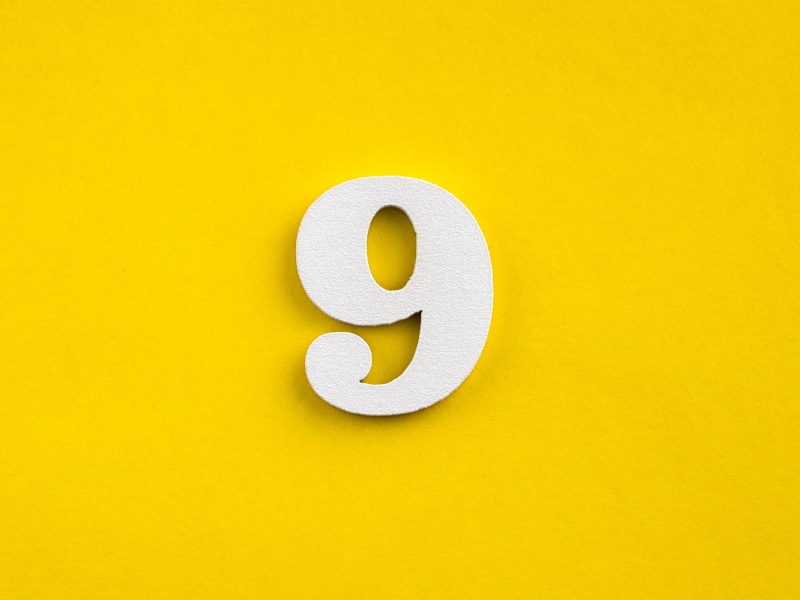 A white 3D number nine against a yellow background.