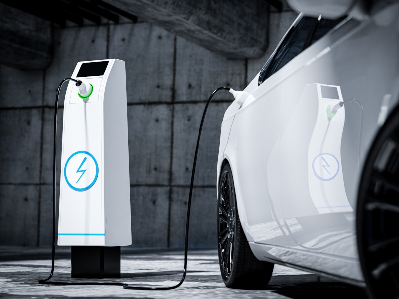 A grey background with a white electric vehicle charger charging a while EV car.