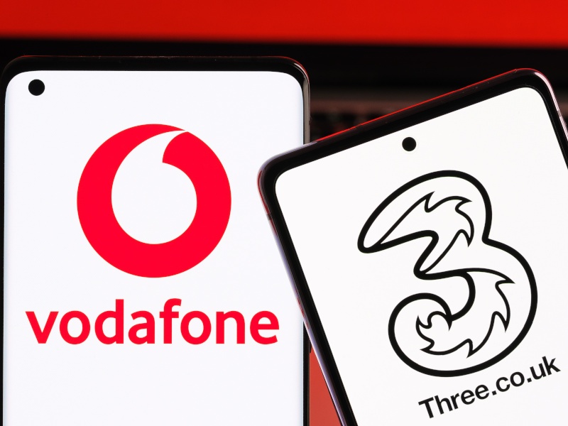 Logos of Vodafone and Three on two separate smartphones placed together