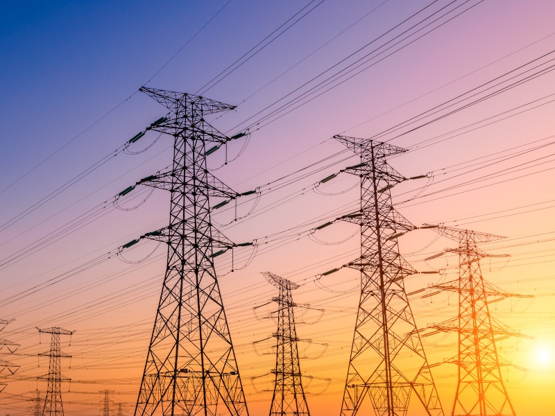 Electricity towers lined up against a sunset.