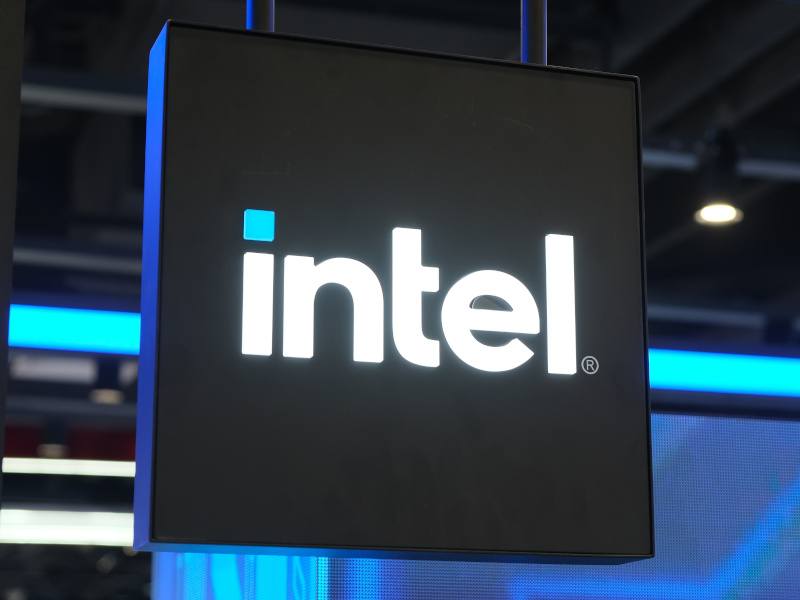 A black sign with the white Intel logo on it. There are blue lights in the background.