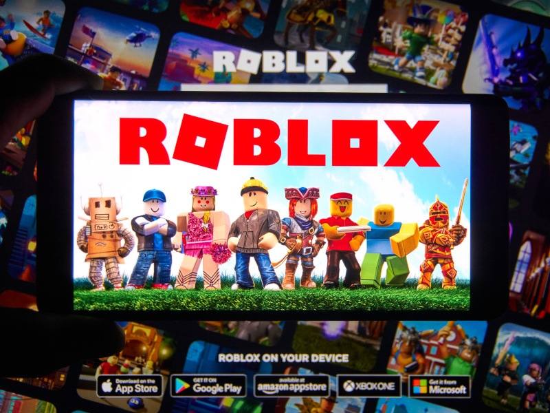 Roblox logo and app on a mobile screen in a hand.