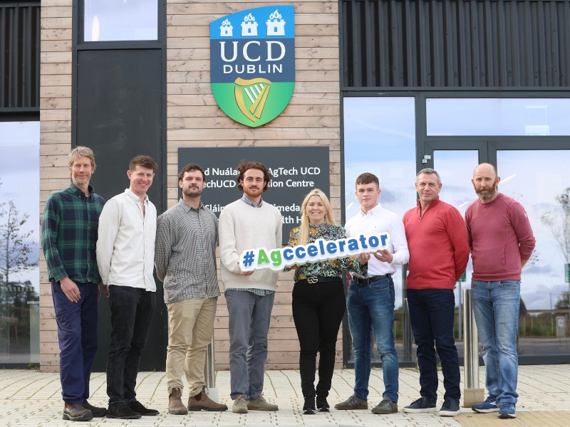 Eight people – seven men and one woman – stand in a line smiling in front of an AgTech UCD building. They are holding a sign that says #Agccelerator.