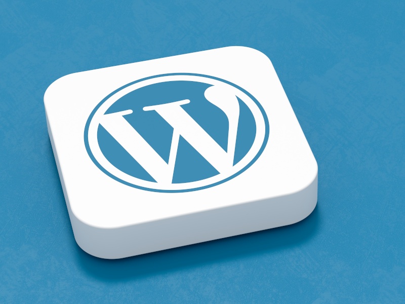 A cartoon-style image of the WordPress W logo on a white tile. The tile is sitting on a blue background.