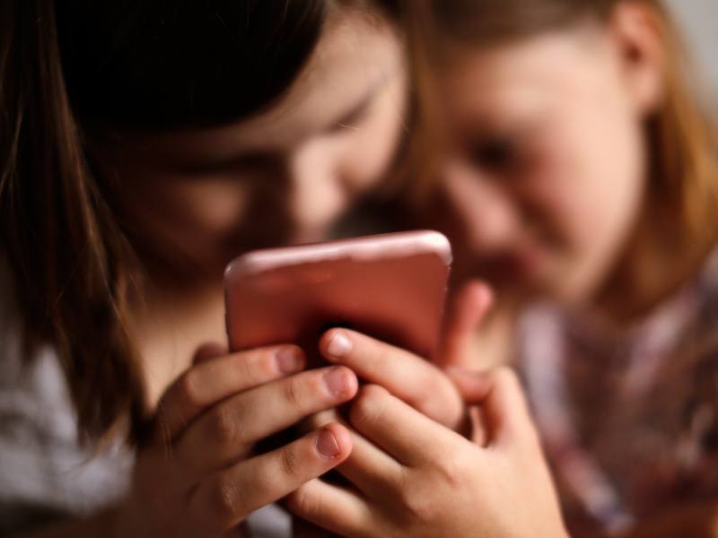 Two children holding a smartphone.