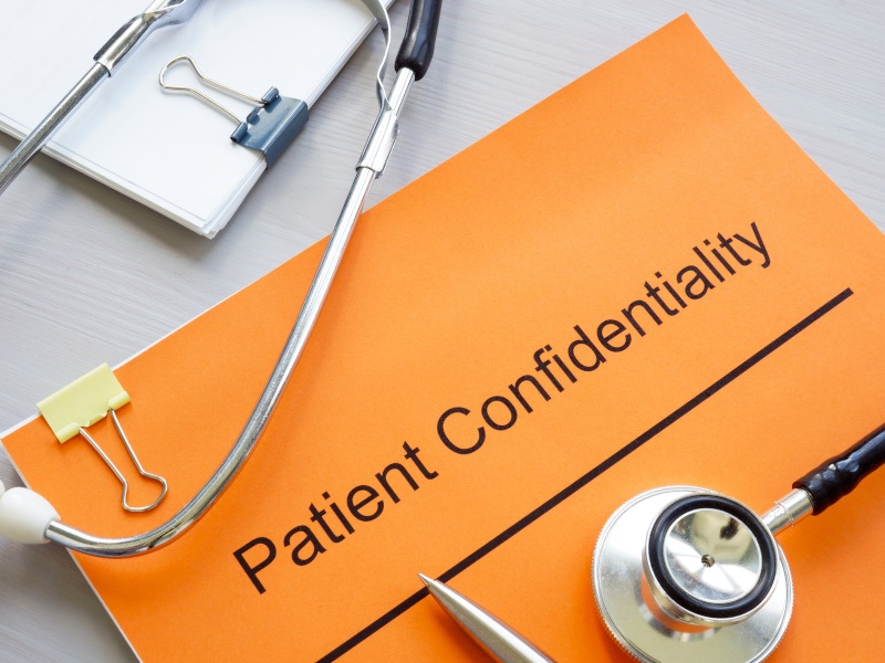 An orange patient confidentiality document cover with a medical stethoscope on top.