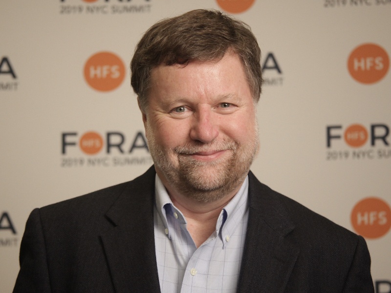 A headshot of a man smiling at the camera while wearing a suit. He is Bob Sutor.