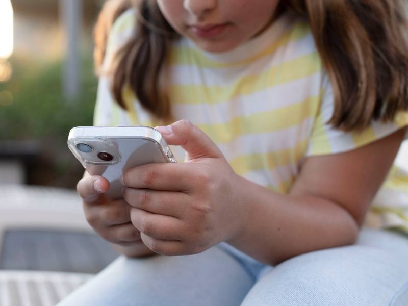 A child holding a smartphone and looking into it.