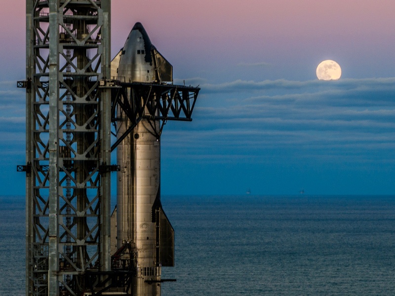 The rocket in its launch pad with the moon in the back.