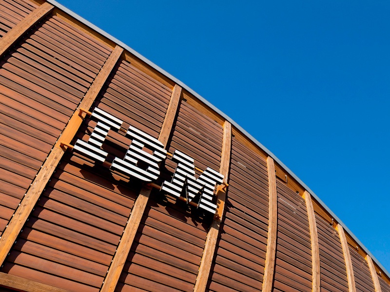 An upward-facing shot of a large IBM logo sign on a wooden structure against a clear blue sky.