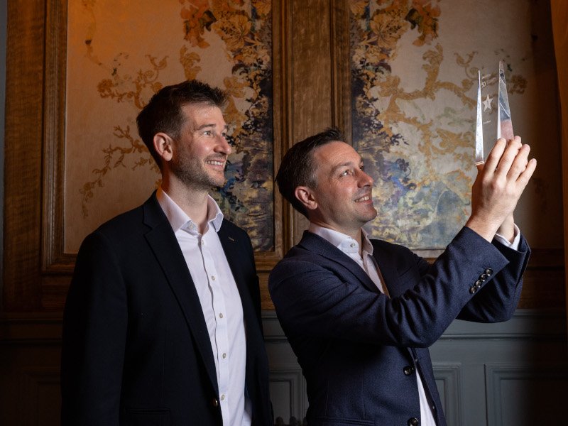 Two men looking to the side into a transparent award.