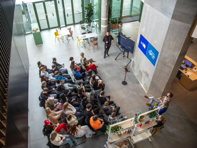 An overhead shot of students sitting in a few rows of chairs, looking at a seminar taking place.