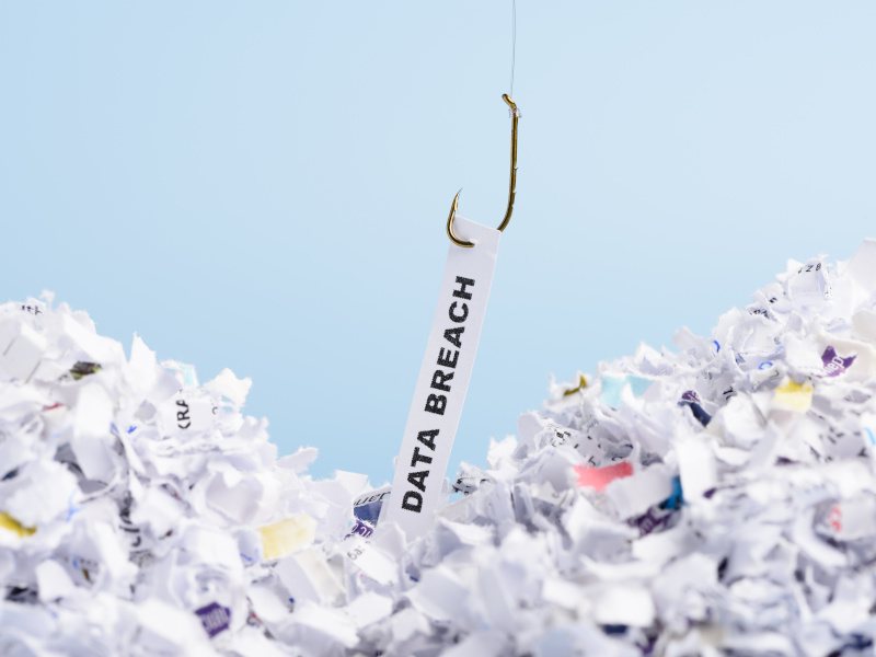 From a pile of crumbled papers, a hook is picking a piece that reads "data breaches".