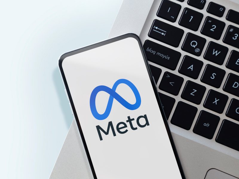 Meta logo on a smartphone on top of a laptop keyboard.