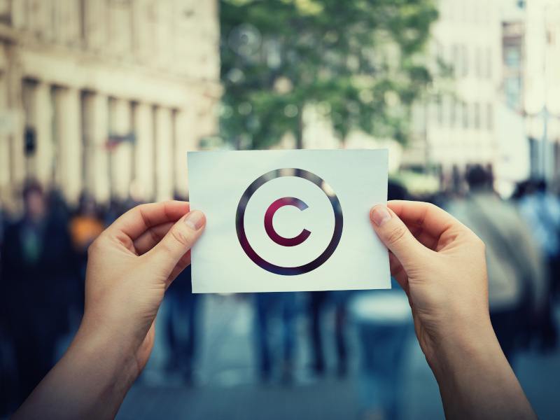 Hands hold paper with copyright symbol.