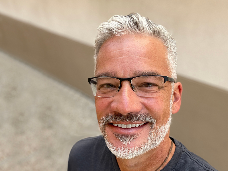 A close-up headshot of Edward Perez. He has glasses and a beard and wears a blue t-shirt.