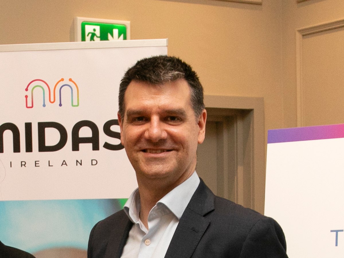 A headshot of a man in a suit standing in front of a banner that says Midas Ireland.